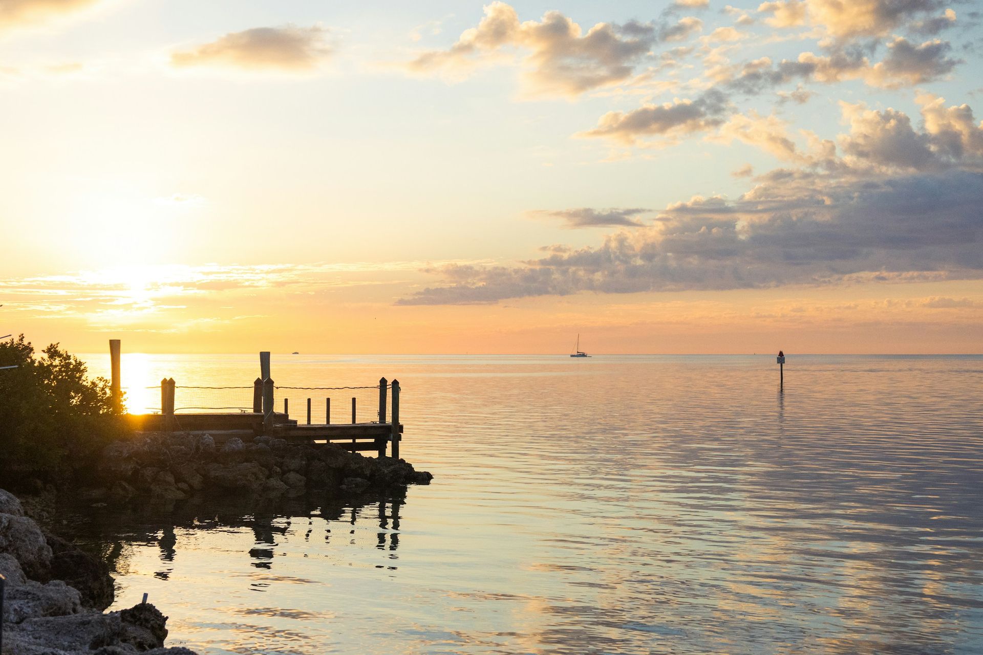 Golden sunset over calm Gulf water with a small wooden dock