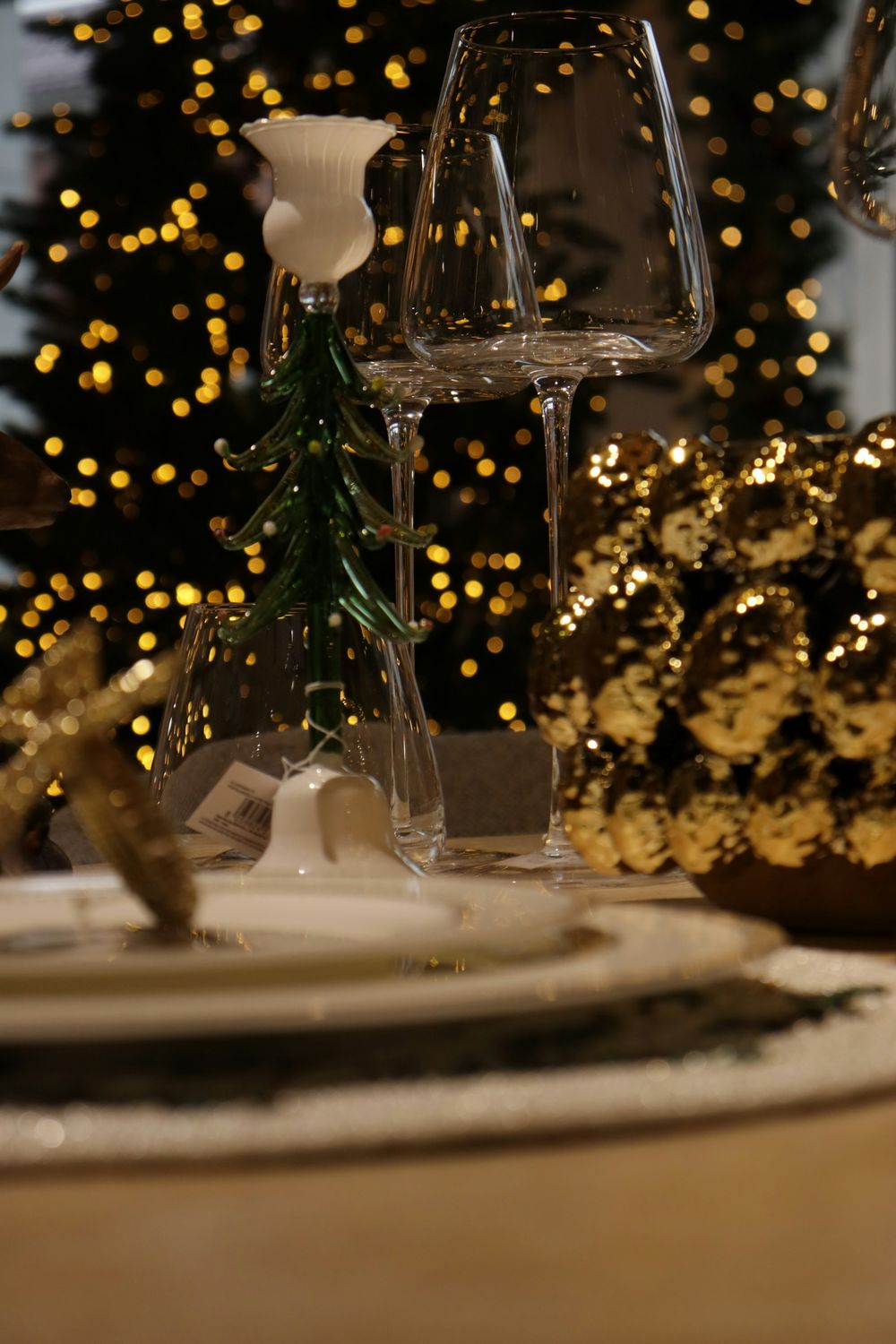 Holiday table setting with glassware in front of Christmas tree lights